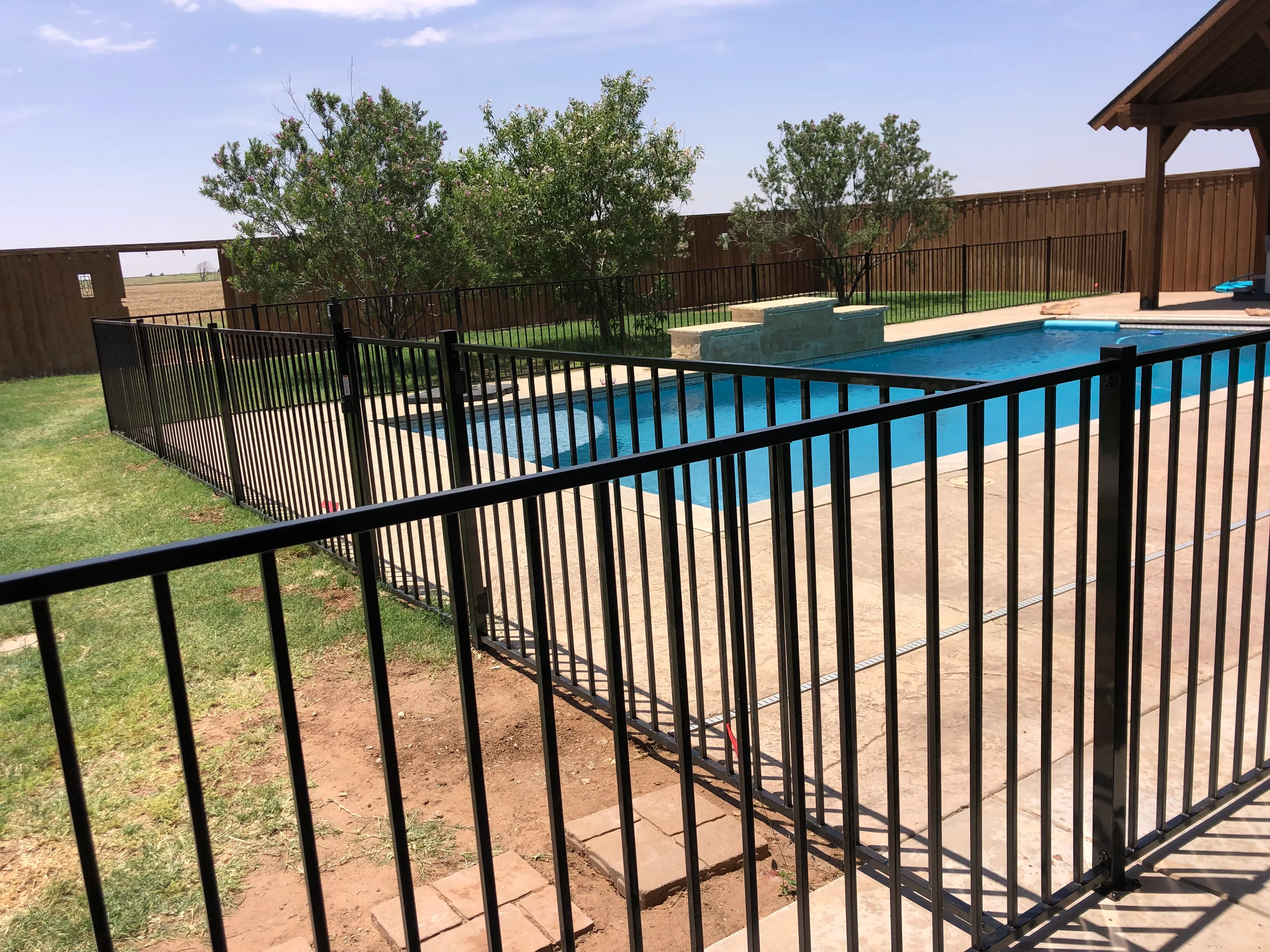Side view of black ornamental pool enclosure fence with decorative pickets