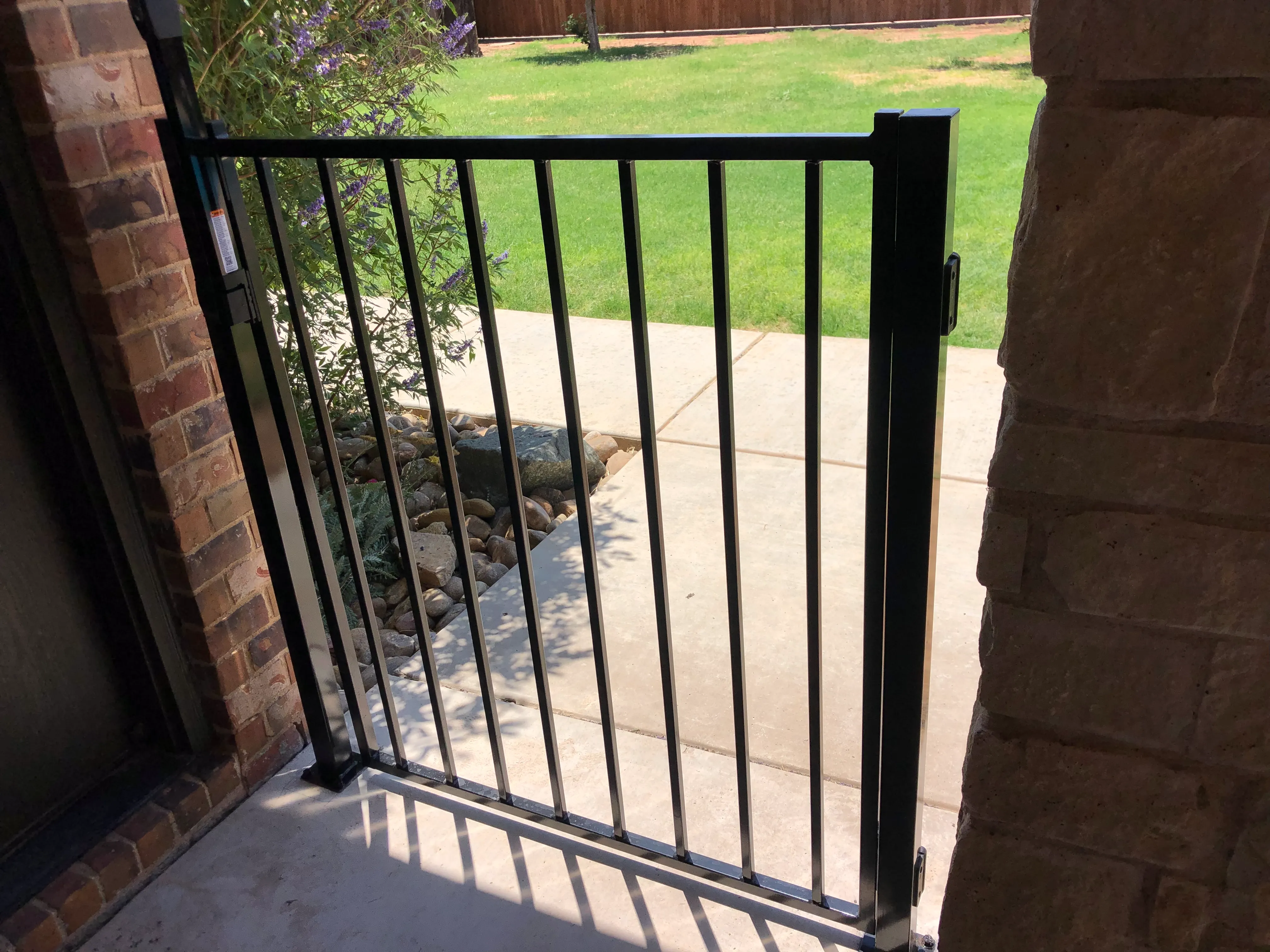 Custom metal privacy fence integrated into stone retaining wall