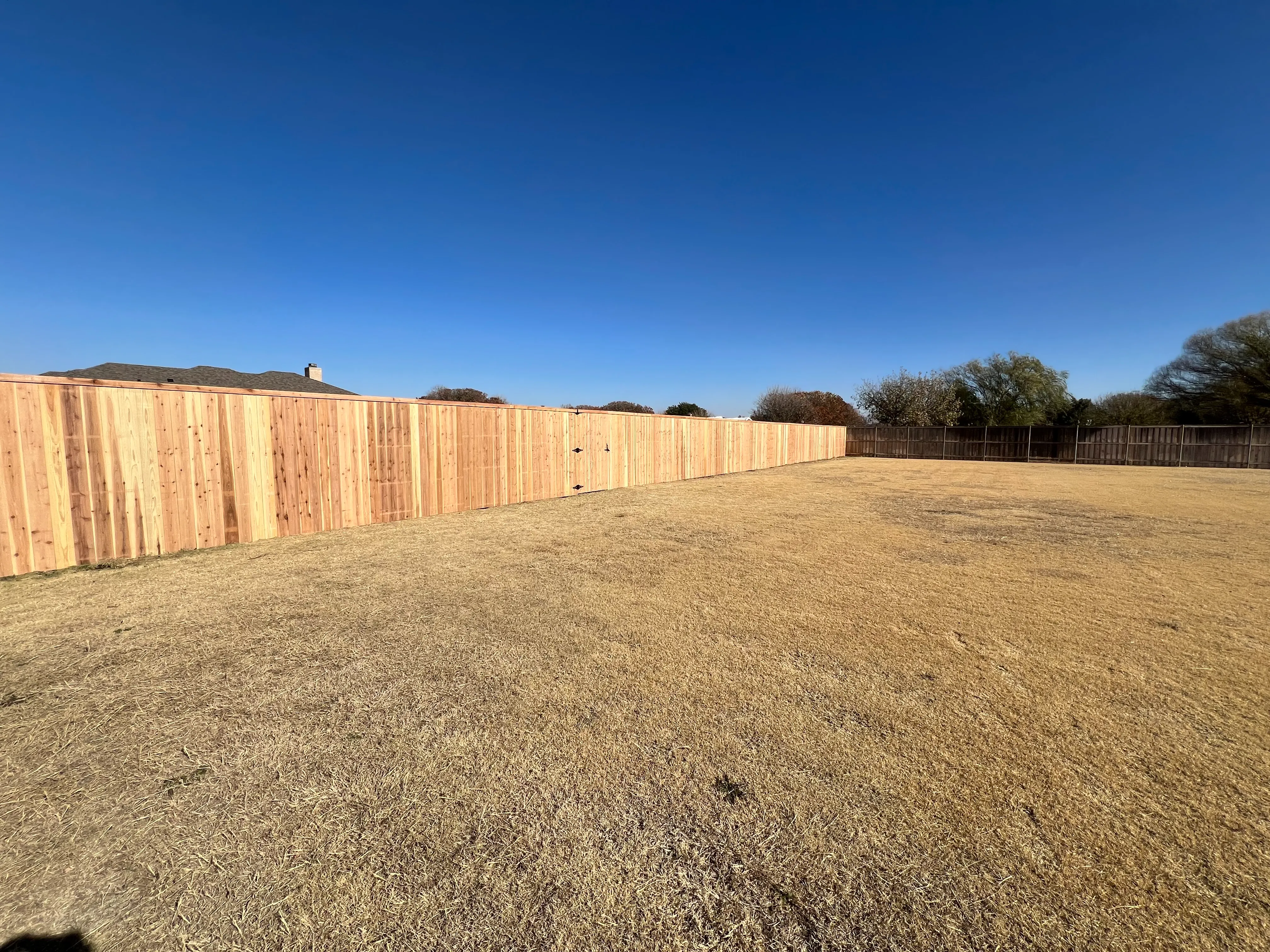 Driveway entrance with stained cedar privacy fence and matching style