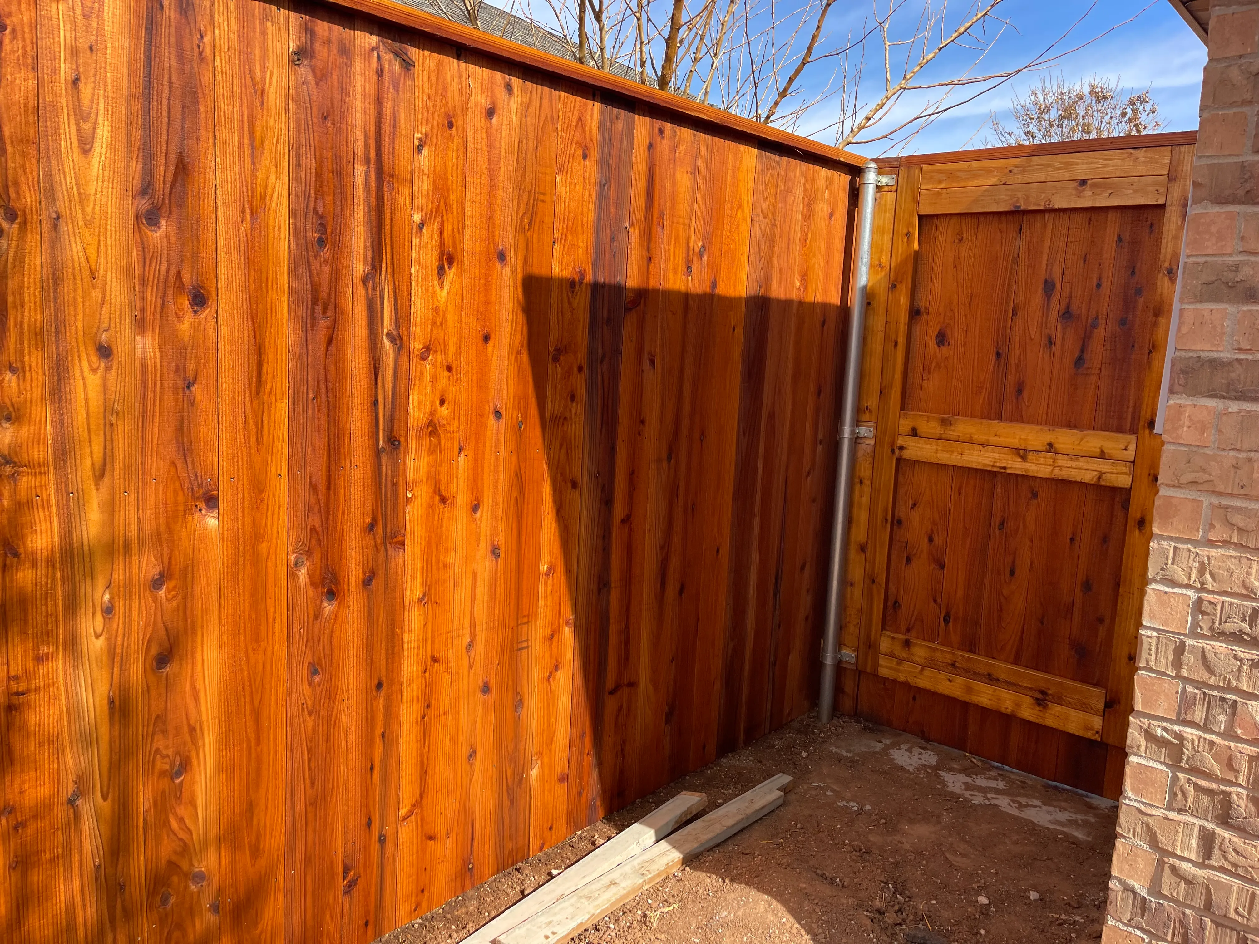 Cedar privacy fence with crown cap and Cedar Tone stain installed in Lubbock TX