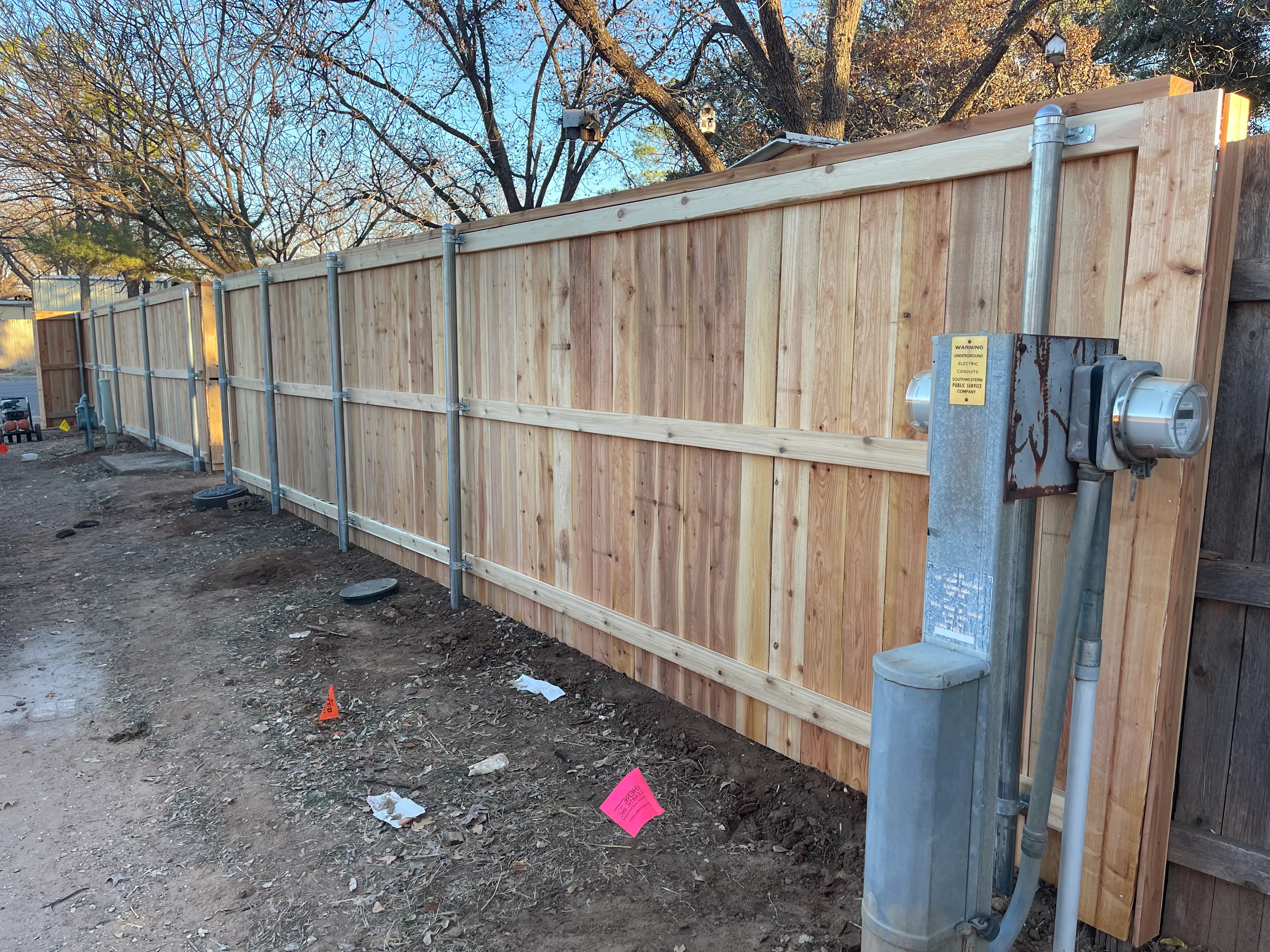 Driveway-side view of cedar fence installation and gate approach