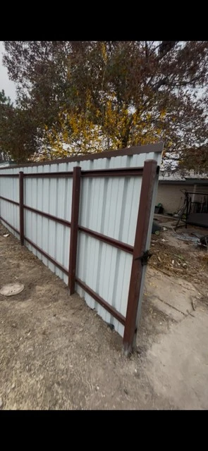 Backside view of metal fence showing vertical support structure and Tudor Brown cap