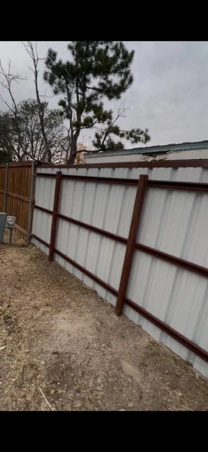 Backside view of metal fence showing vertical support structure and Tudor Brown cap
