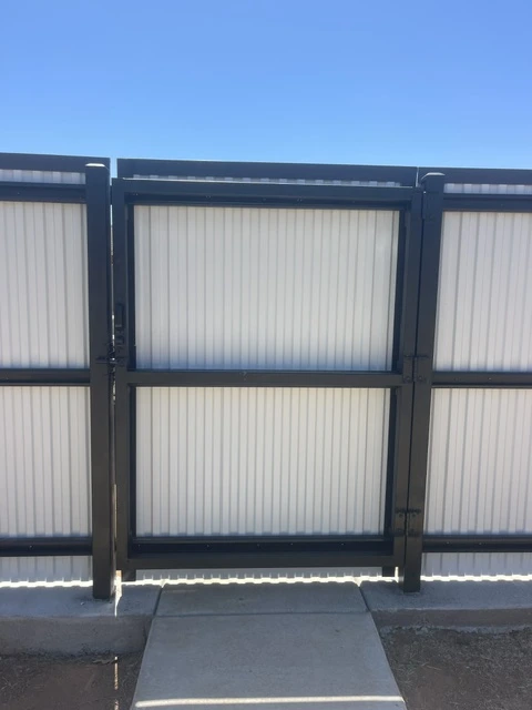 Custom black metal fence with welded steel frame and vertical ribbed panels featuring a secure walk gate, installed by a professional fencing contractor.