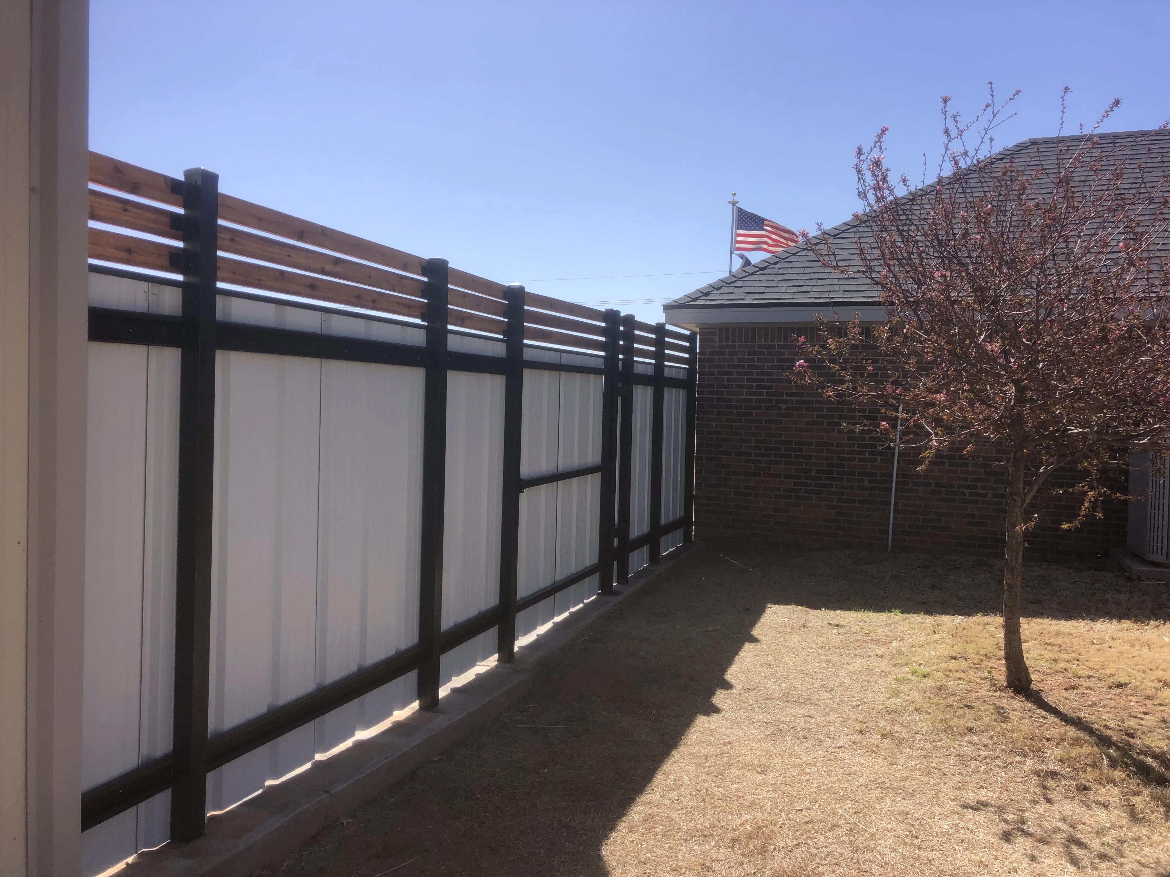 Backside view of hybrid metal and cedar fence showing vertical support structure