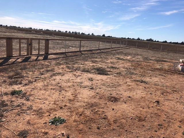 Custom 4-foot ranch rail fence with galvanized wire mesh stretching across a large acreage property featuring cedar posts and agricultural fencing construction
