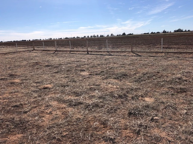 Wood ranch rail fence with welded wire backing installed on rural land providing secure livestock fencing, pet containment, and open property views