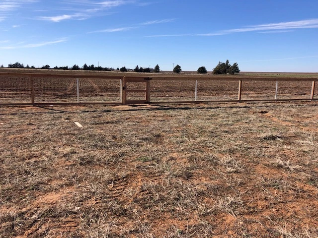 Cedar ranch rail fence featuring a custom pedestrian gate with wire mesh fencing installed on a large rural property for livestock and pet security