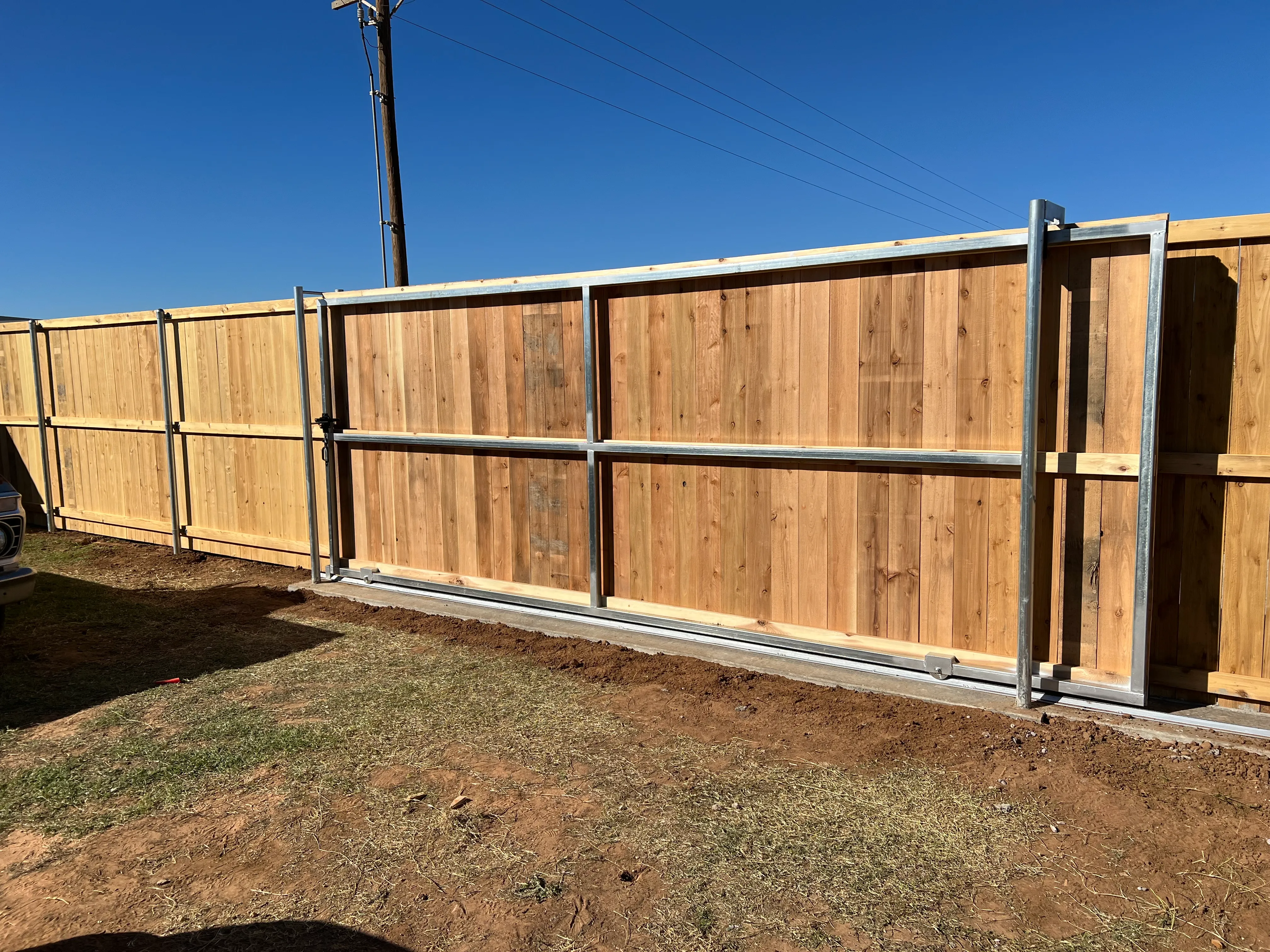 Sliding steel frame driveway gate mated to 7-foot stained cedar privacy fence